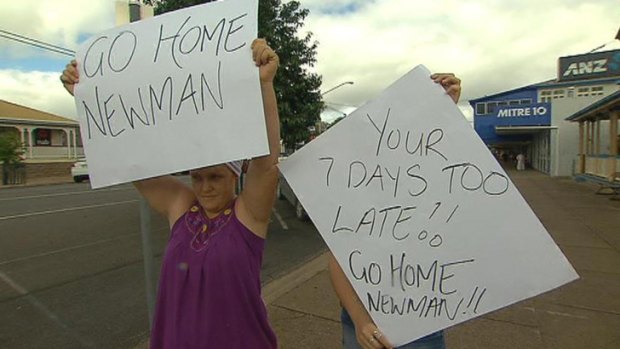 Angry Gayndah residents hold up signs as Premier Campbell Newman visits the town.