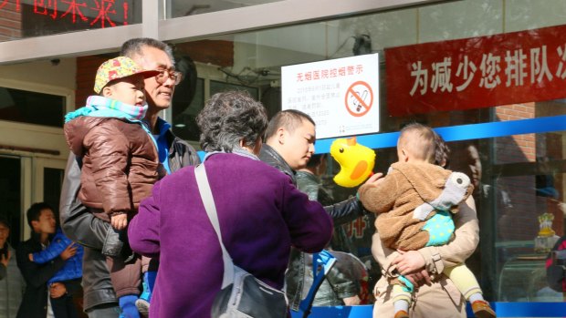Families with young children gather outside a paediatric hospital in central Beijing. 