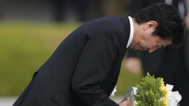 Japanese Prime Minister Shinzo Abe bows as he lays a wreath during the Hiroshima Peace Memorial Ceremony at Hiroshima Peace Memorial Park on August 6, 2016.