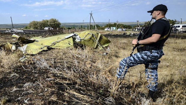 A pro-Russian militant  stands guard near a piece of debris.