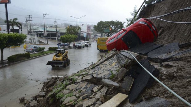 A car lies on its side after a portion of a hill collapsed due to heavy rains in the Pacific resort city of Acapulco, Mexico.
