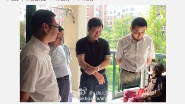 A screen shot of the digitally manipulated image that went viral in China, depicting local officials visiting with an improbably small elderly woman.