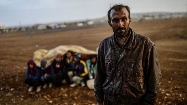 Seeking safe haven: A Syrian Kurdish man stands next to other refugees taking cover from the rain.