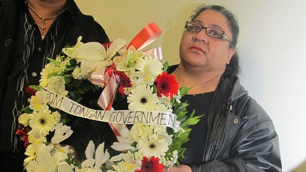 A woman at the ceremony holds a wreath from the Tongan Government.