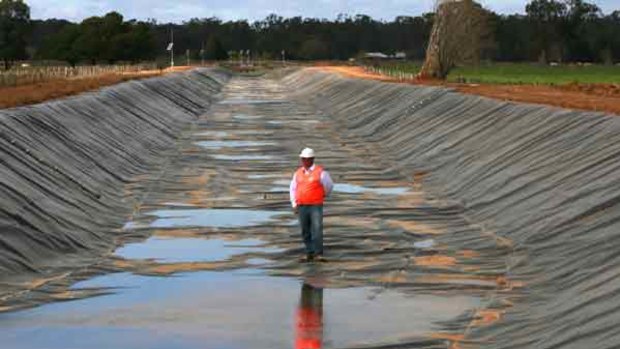 John Harvey, project manager for the irrigation channel rehabilitation works, inspects a channel lined with plastic near Shepparton.