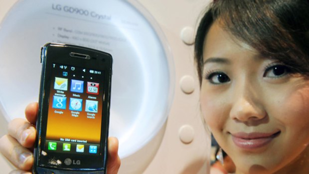 A woman holds an LG GD900 Crystal mobile phone, said to be world's first transparent touch phone displayed at the CommunicAsia 2009 show in Singapore in June. LG will tomorrow announce that they are launching an app store for their phones.