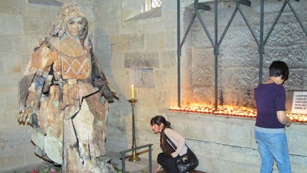 Flowers are laid at the base of a hand carved wooden sculpture of Mary MacKillop inside St Stephen's Cathedral, Brisbane.