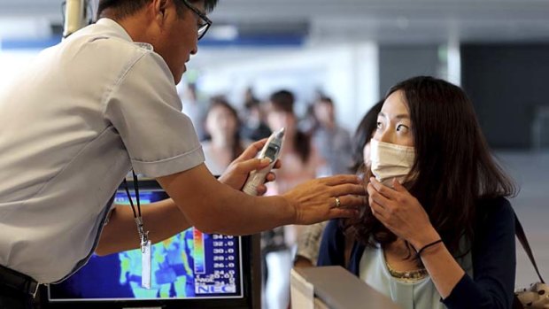 A quarantine officer checks body temperature of a passenger against possible infections of Ebola virus at the Incheon International Airport in South Korea.