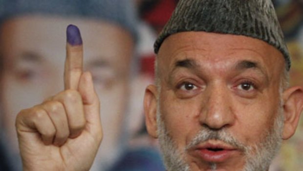 ‘‘No more corrupt than last year’s election’’ ... Hamid Karzai displays his inked finger after voting in Kabul on Saturday.