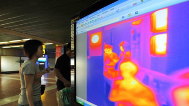 Passengers from an international flight have their temperature checked as they pass a thermal scanner monitor upon arrival in Jakarta.