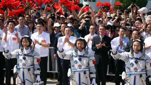 National heroine ... Major Liu Yang waves to the crowd alongside fellow astronauts Liu Wang and mission commander Jing Haipeng.
