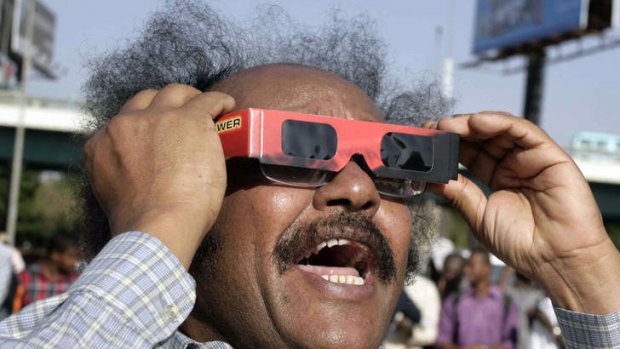 A Sudanese man reacts as he looks through tinted glasses towards the sun to watch a partial solar eclipse over the Sudanese capital Khartoum.