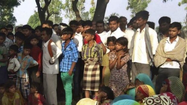 Indian villagers gather around the bodies of two teenage sisters hanging from a tree in Katra village in Uttar Pradesh state, India. The victims' families allege that local police were shielding the attackers.