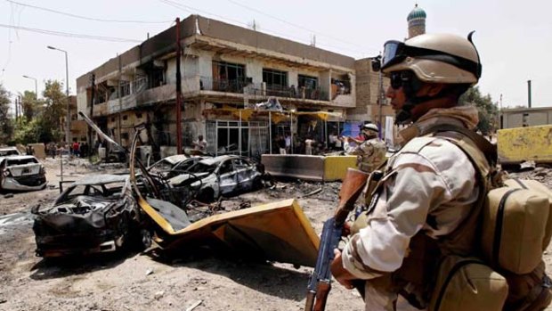 An Iraqi Army soldier stands guard at the site of a car bomb attack in Baghdad.