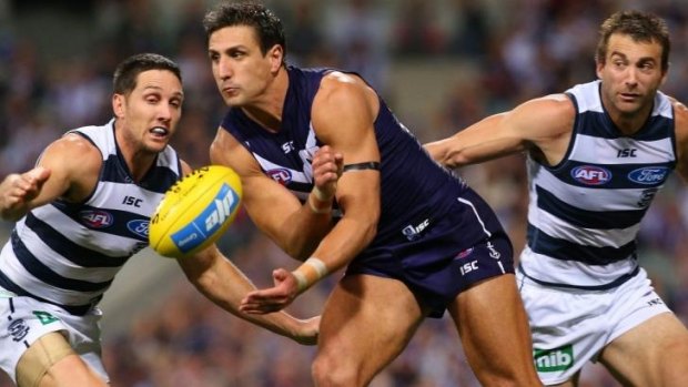 Matthew Pavlich handballs as Cats Harry Taylor and Cory Enright approach.