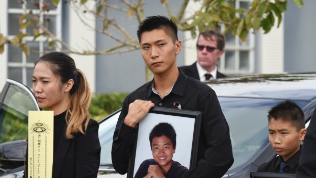 Jason Wang, centre, holds a picture of his brother Peter, along with his younger brother, Alex, after his brother's funeral.
