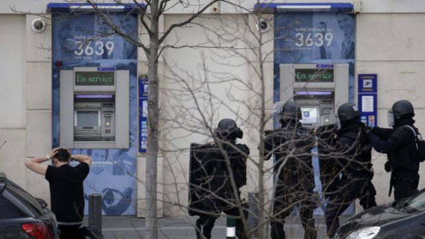 A suspect is detained by special police forces as a hostage situation is resolved at the post office in Colombes, near Paris