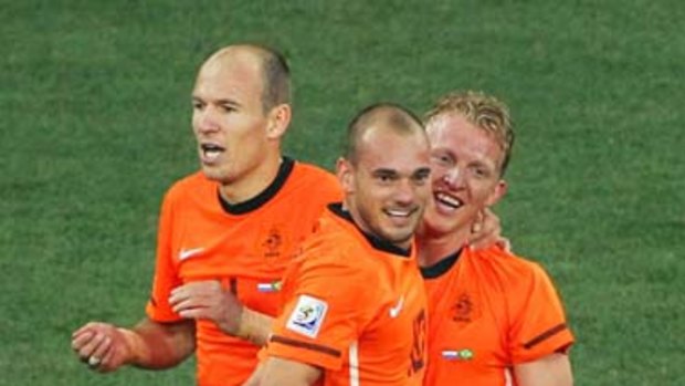 Wesley Sneijder celebrates the own goal by Felipe Melo of Brazil with teammates Dirk Kuyt and Arjen Robben.