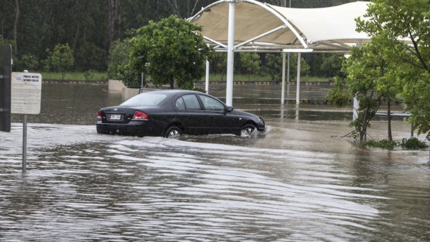 A car navigates flooding in a Burpengary shopping centre carpark in Brisbane on Friday.