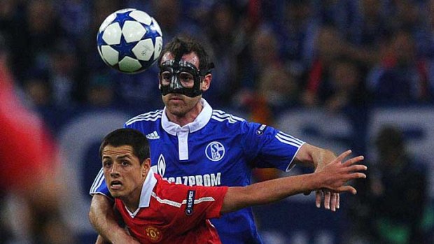Mask of sorrow ... Manchester United striker Javier Hernandez holds off a challenge from Schalke's masked man, Christoph Metzelder.
