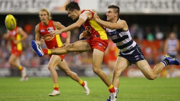 Alex Sexton of the Suns kicks as Shane Kersten of the Cats approaches.