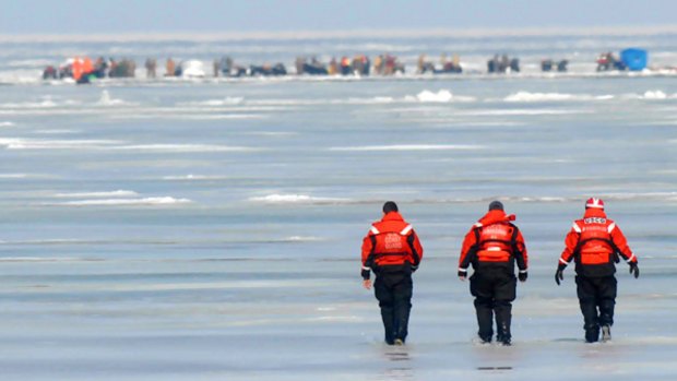 Members of the US Coast Guard walk across the frozen Lake Erie as they attempt to reach stranded fishermen.