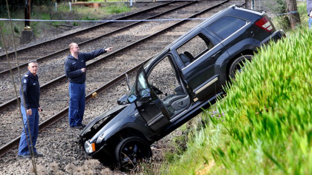 Police officers analyse the four-wheel-drive that ended up next to rail lines.