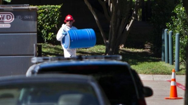 A member of the emergency response team from Protect Environmental Services carries a plastic barrel to be used to collect contents from the apartment of a second Texas nurse who has tested positive for Ebola.