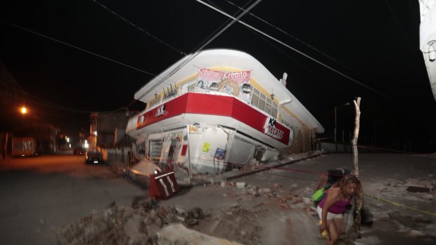 A woman walks past a collapsed building in Jojutla, Morelos state, Mexico.
