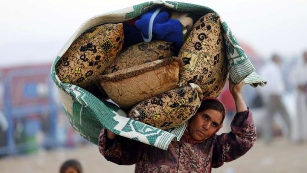 A Syrian Kurdish woman carries her belongings after crossing into Turkey near the southeastern town of Suruc.