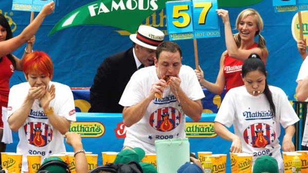 Joey Chestnut, centre, and his arch rival, Takeru Kobayashi, left, battle to eat the most hot dogs at the annual hot dog eating contest in the Brooklyn borough of New York.