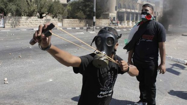 A Palestinian protester uses a slingshot during clashes with Israeli border police at a protest against the Israeli offensive in Gaza.
