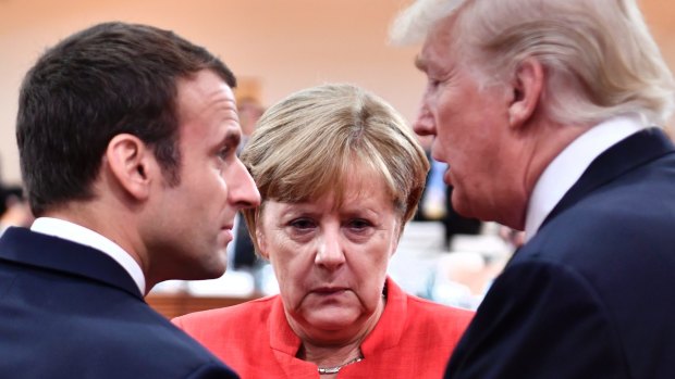 France's Emmanuel Macron, Germany's Angela Merkel and US President Donald Trump engage in conversation at the start of the first working session of the G20 on Friday.
