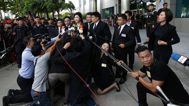 Thailand's former Prime Minister Yingluck Shinawatra talks to the waiting media while being watched by Thai security on Tuesday.