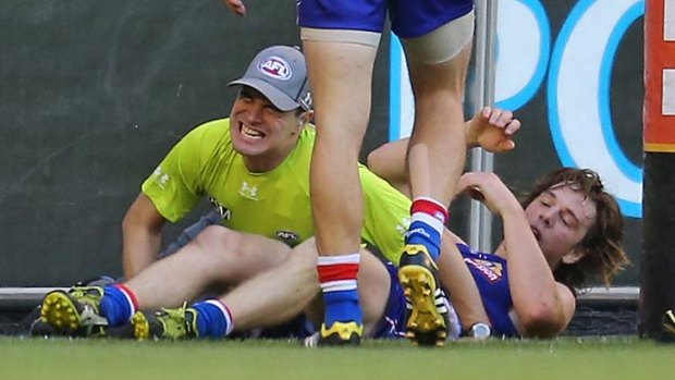 Painful end: Goal umpire Courtney Lai winces in pain after suffering a knee injury in an incident involving Bulldog Liam Picken.