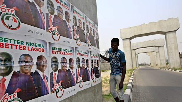 A man looks at campaign posters, near mono rail line pillars under construction in Lagos, Nigeria.