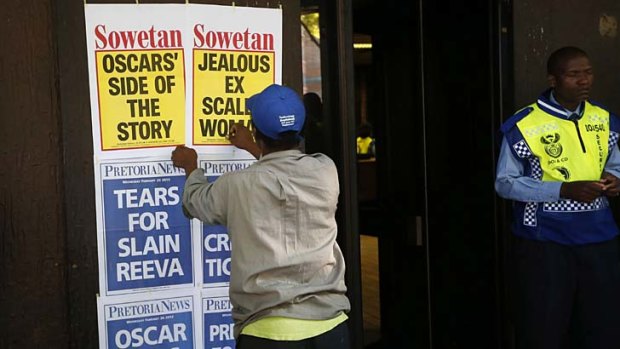 A newspaper vendor puts up posters outside the Pretoria Magistrates court.