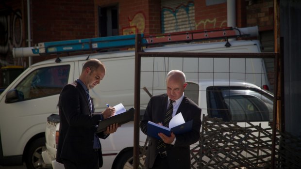Paul Rowe (left) and Dave Butler typify the public's idea of homicide squad detectives, carrying bound folders and wearing darks suits.