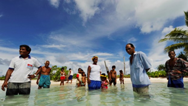 Villagers on the island of Abaiang stand in the sea where their homes used to be.