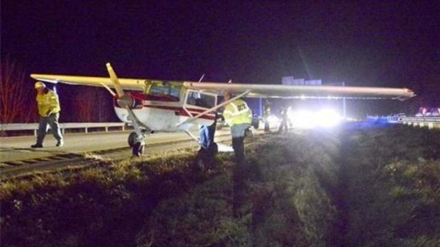 Maine State police and transport officials look over a Cessna that made a emergency landing on I-295 near Falmouth during evening rush hour traffic.