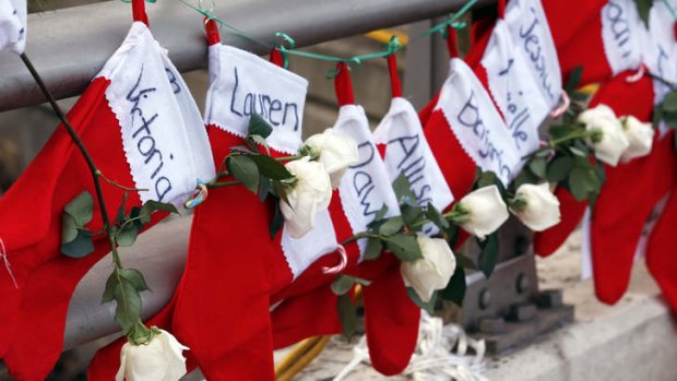 Christmas stockings with the names of shooting victims hang from railing near a makeshift memorial in Sandy Hook.