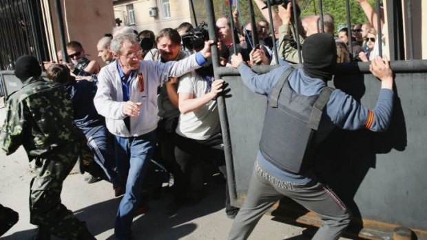 Pro-Russian activists break through the gate in front of the television station in Donetsk.