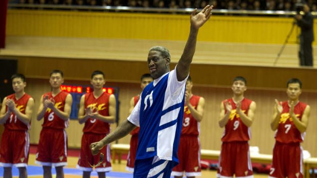 Dennis Rodman waves to North Korean leader Kim Jong Un, seated above in the stands, after singing Happy Birthday to Kim before an exhibition basketball game with U.S. and North Korean players at an indoor stadium in Pyongyang.