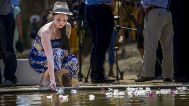 Bronte Forrester, 17, who lost her home in the 2003 fires leaves a flower in the pool at the bushfire memorial on Friday.