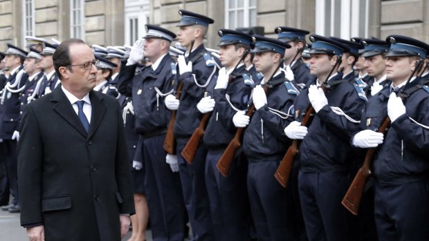 French President Hollande reviews a police honour guard at the Paris prefecture during a ceremony to pay tribute to the three fallen police officers.