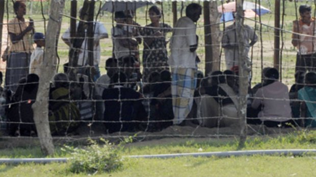 Tamil civilians as they peer from behind a wire fence, inside a camp for displaced people in the northern district of Vavuniya.