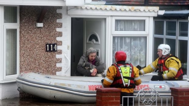 A woman and her dog are rescued by the RNLI or Royal National Lifeboat Institute, from floods as heavy seas and high tides sweep across the country, in Rhyl, Wales.