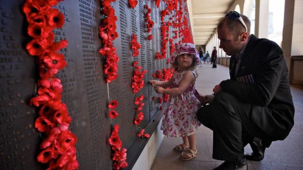 Jamie Bailey and daughter Arabella place a poppy on the Roll of Honour at the Australian War Memorial in Canberra.