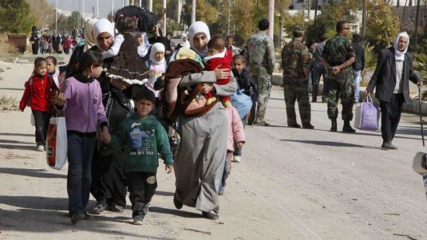 Syrian families leave the besieged town of al-Moadamiyeh, which is controlled by opposition fighters, in Damascus.