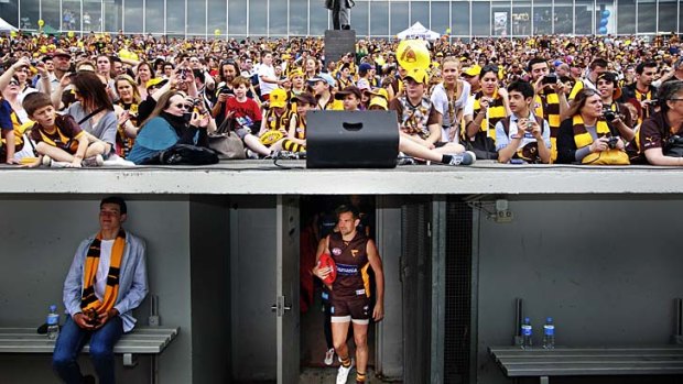A crowd of about 8000 cram in for the Hawks training session; a fan enjoys the moment as Luke Hodge leads the players out.